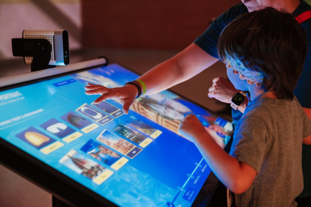 Photo of a parent and child using one of the Leonardo Experience activity kiosks in Curiosity Hall